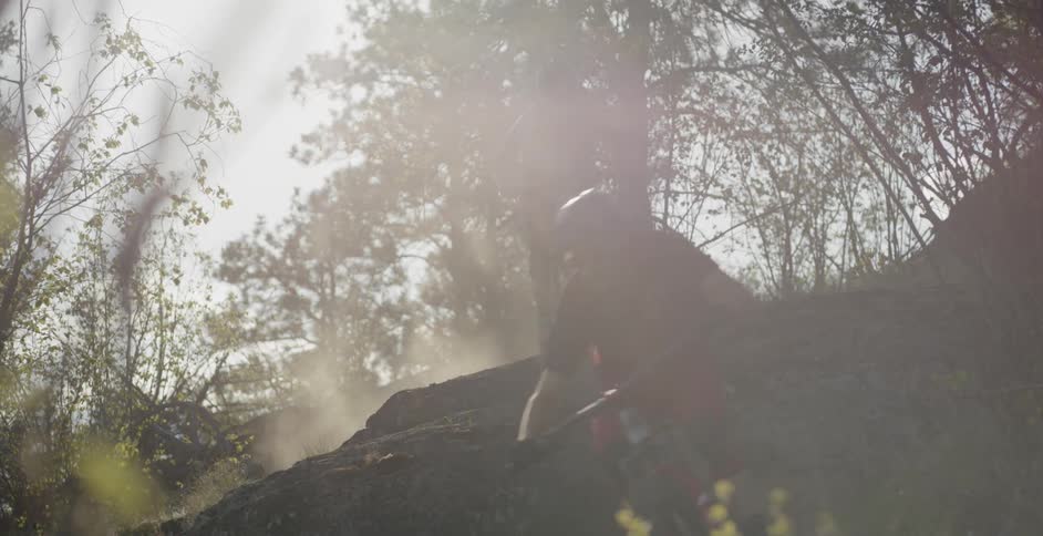 Two riders are speeding down a hillside on mountain bikes during the day