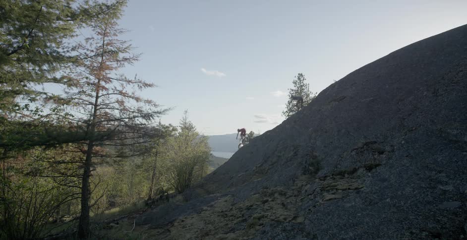 Bicyclists ride down a hill in a forest