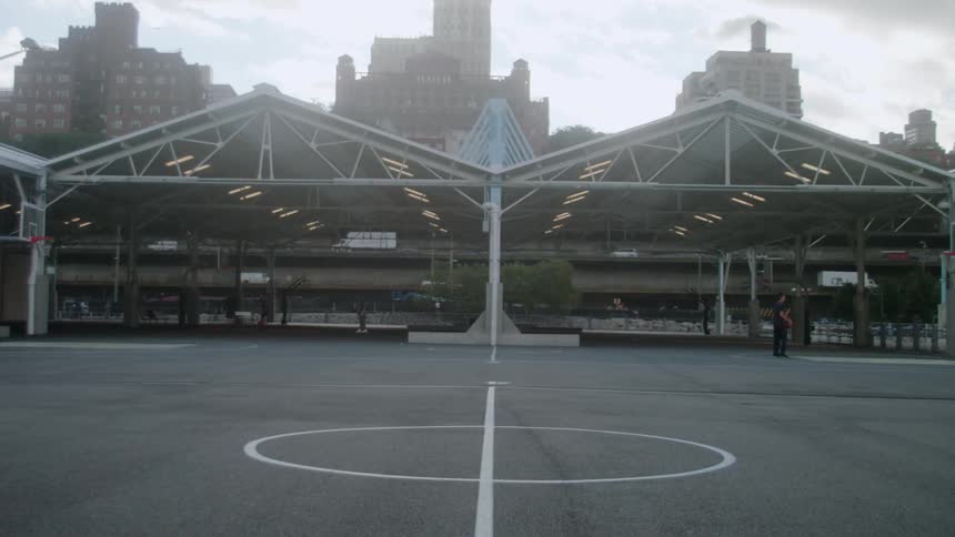 Man is sprinting across outdoor basketball court in the city