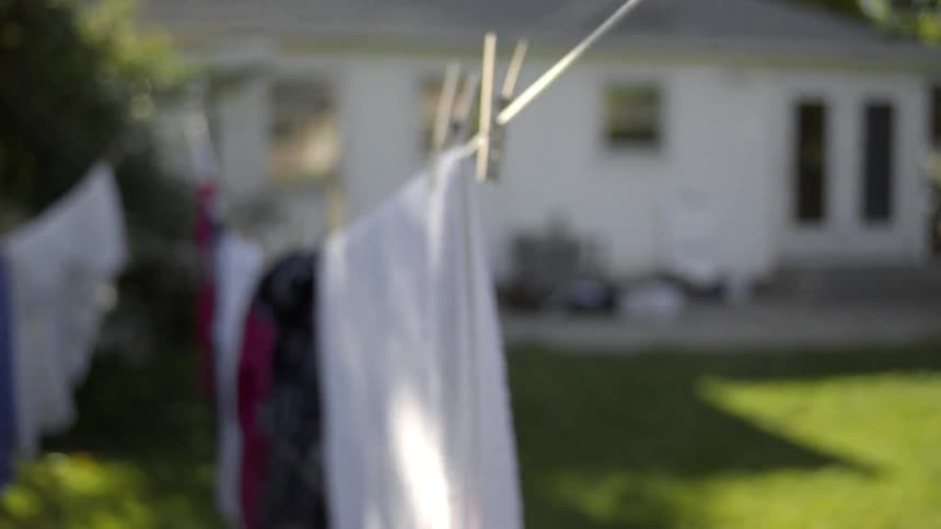 A man runs by a clothesline and grabs a pair of jeans
