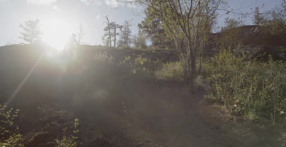 Bicyclists ride down a hill at sunset