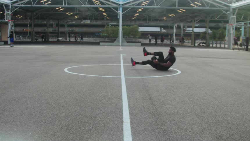 Man does sit ups on a basketball court