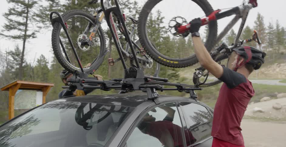 Man and woman remove bicycles from a roof rack in the woods