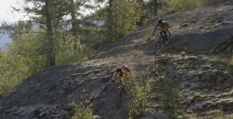 Two people ride bikes on hilly bumpy terrain