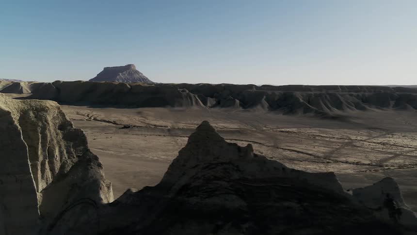 Flat hills and large rocks sit under a blue sky