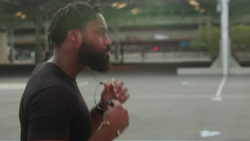 Man puts in earphones on an outdoor basketball court