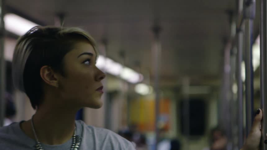 A girl with white and black hair bites her lip on the subway