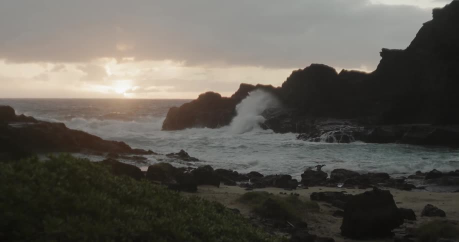 Waves crash into the rocks under a dark cloudy sky