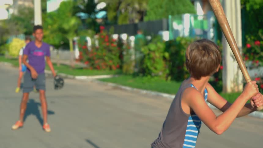 Children are playing baseball in the street