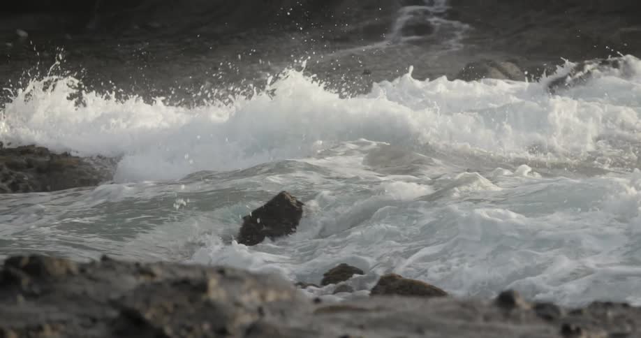 The rough waters splash against the rocks