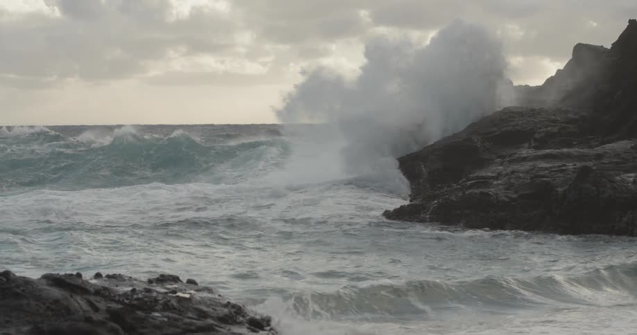 Ocean waves splash up against the rocks on shore