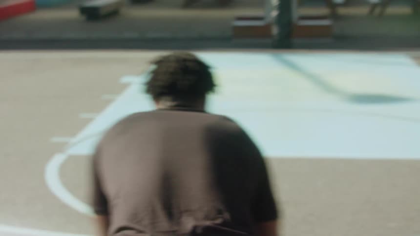 A man is dribbling a basketball on a court by himself