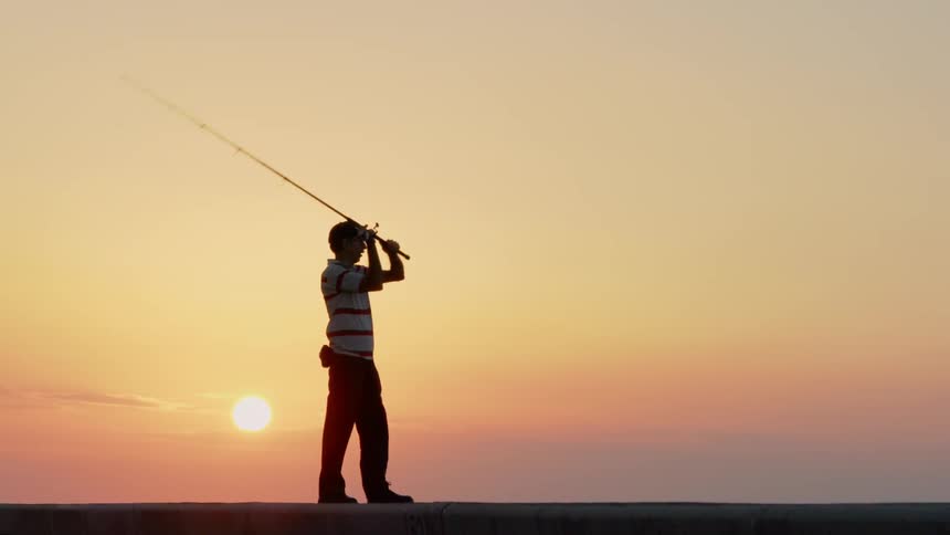 Man casts a fishing pole at sunset
