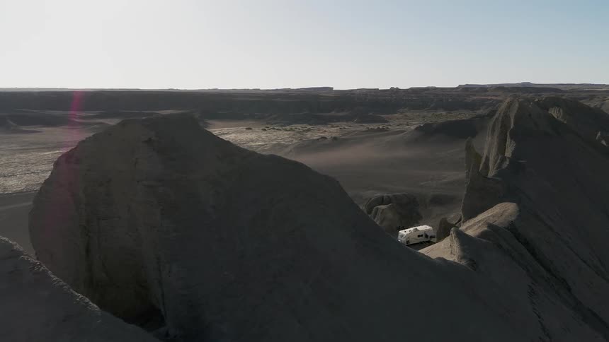 A truck and camper are parked next to desert mountains