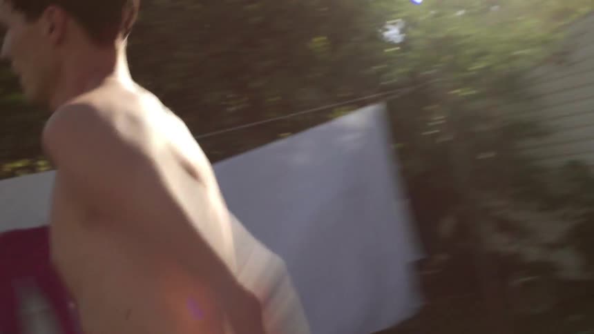 A shirtless man runs by laundry on a clothesline