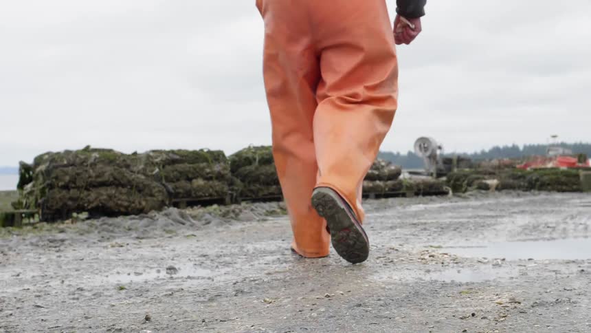 A man in orange waders walks outside