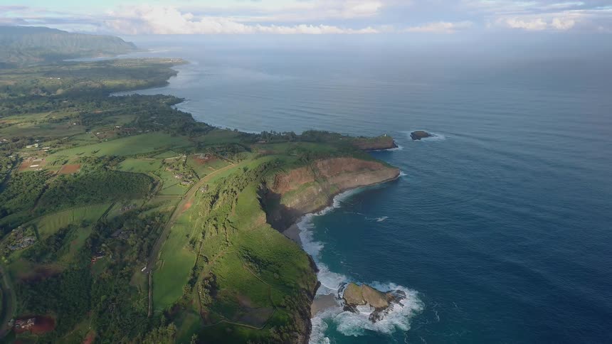 Waves roll into the rocky shore under the sunny sky