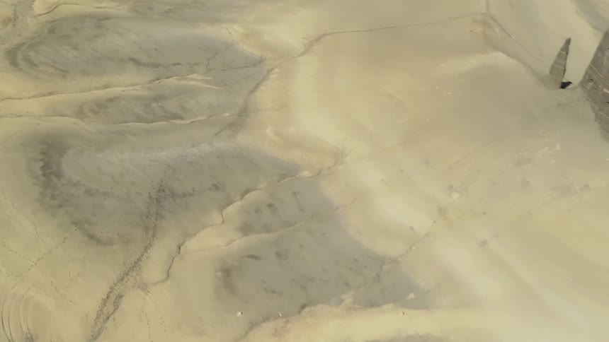 Dry streams and tracks are covering an eroding desert valley in daylight