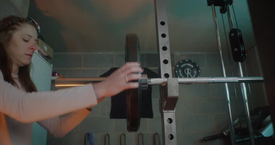 Woman puts a weight on a barbell