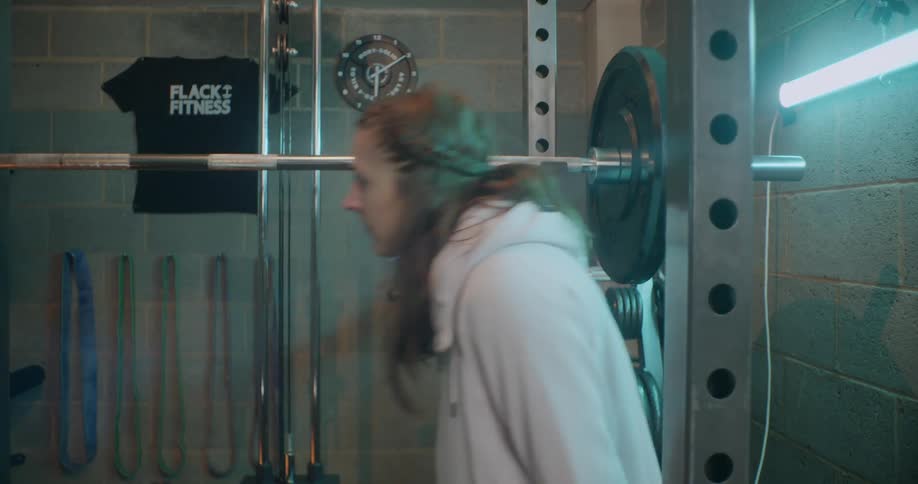 Woman sits down next to weights in a gym
