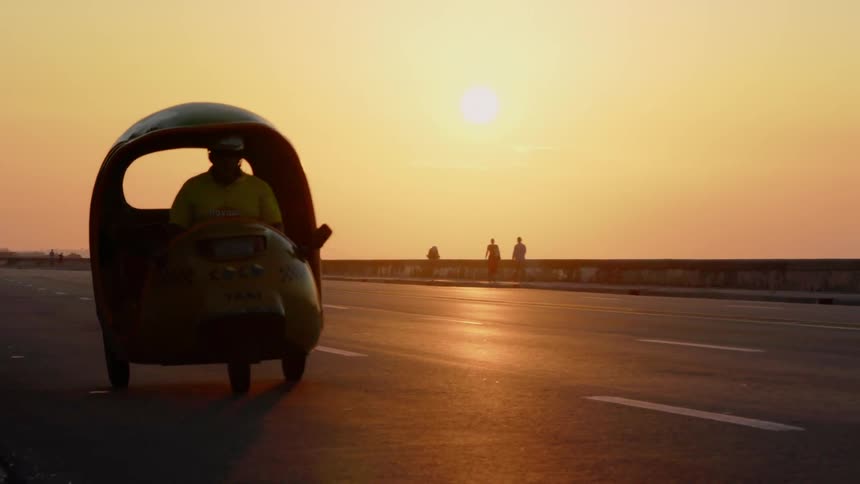 Man drives a rickshaw at sunset