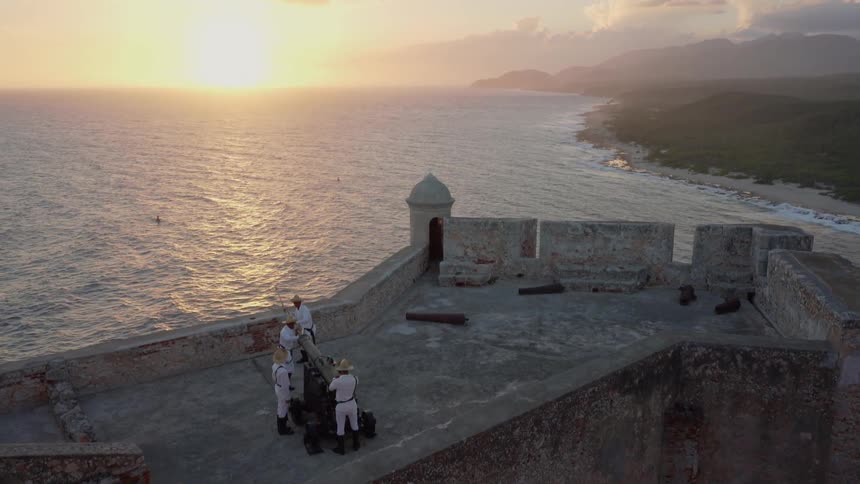 Several people stand on a structure planning to fire a cannon