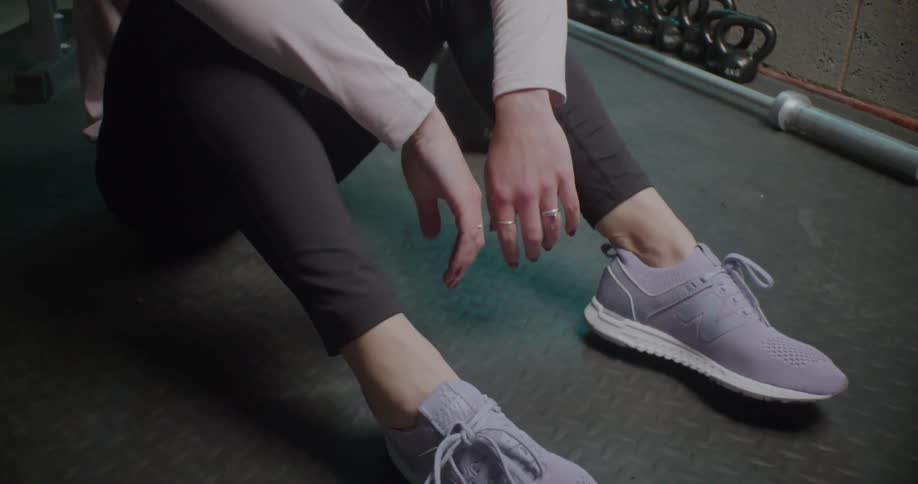 A woman sits on a mat in a gym