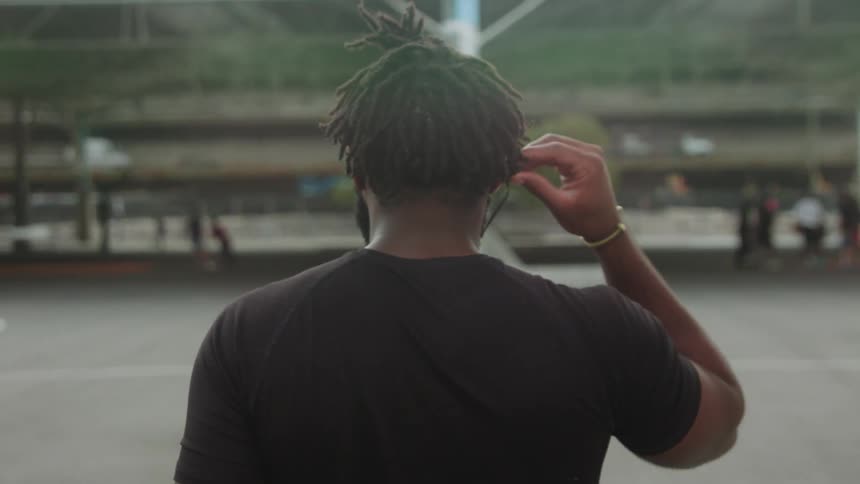 Man in urban setting places earbud in ears