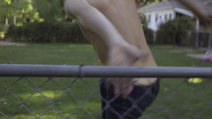 Man running in a yard hops a chain link fence