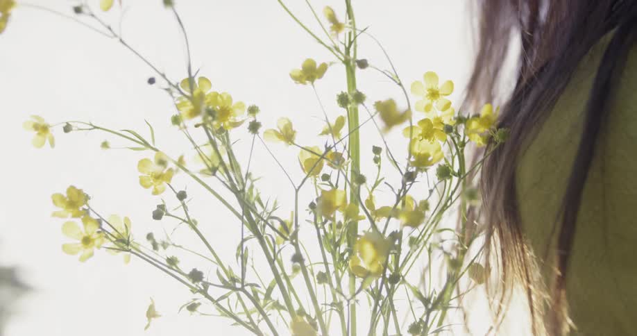 Someone is carrying a bunch of small yellow flowers