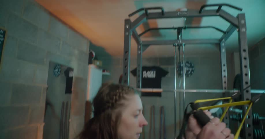 A woman holds onto the handles of an exercise machine and squats