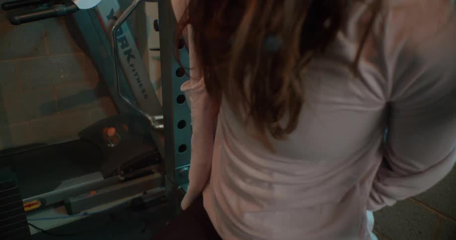 Woman takes off a jacket in a weight room