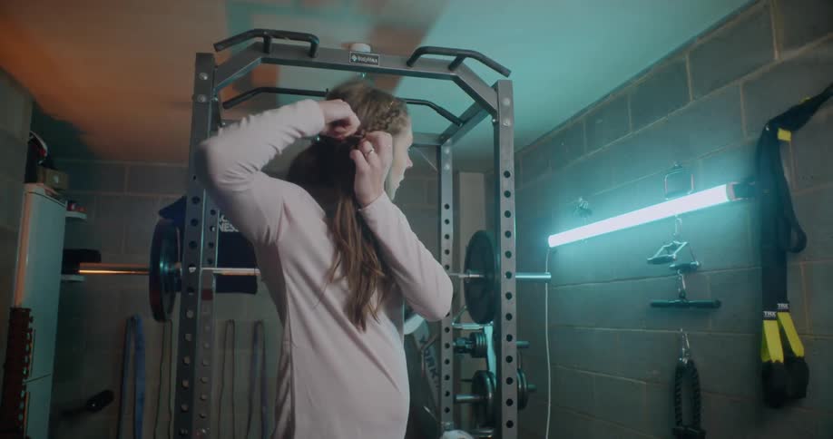 A woman braids her hair in the gym