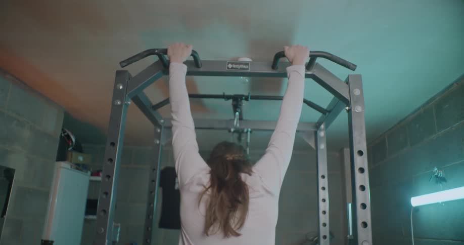 A woman is doing pull ups in the gym