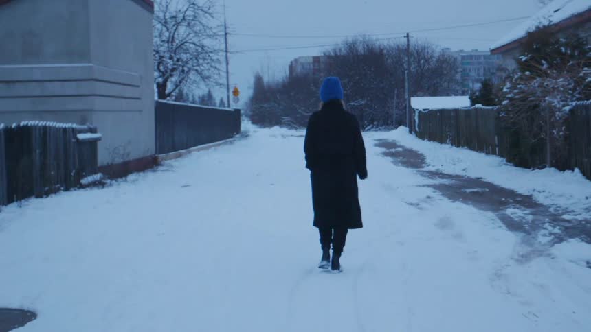 Woman in a long coat walks through the snow