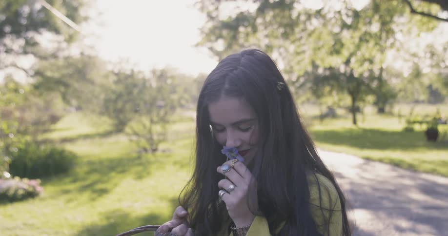 A woman is smelling a flower and smiling