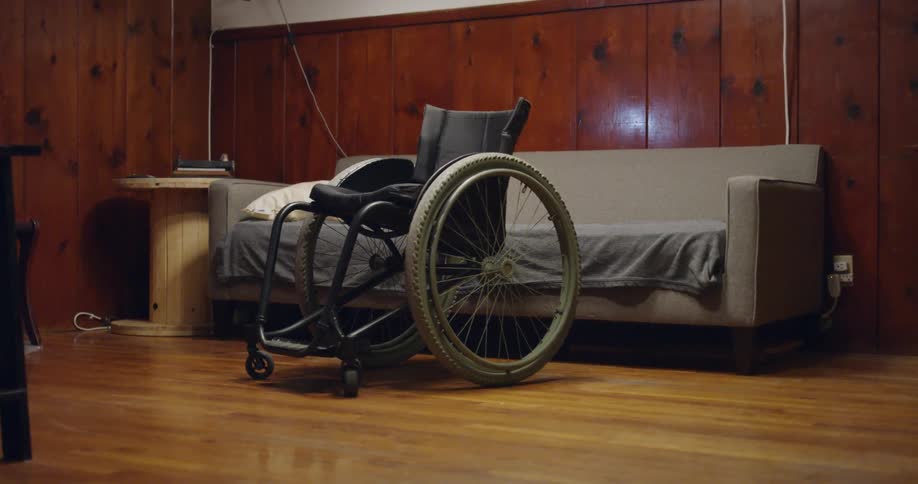 A wheelchair sits next to a couch