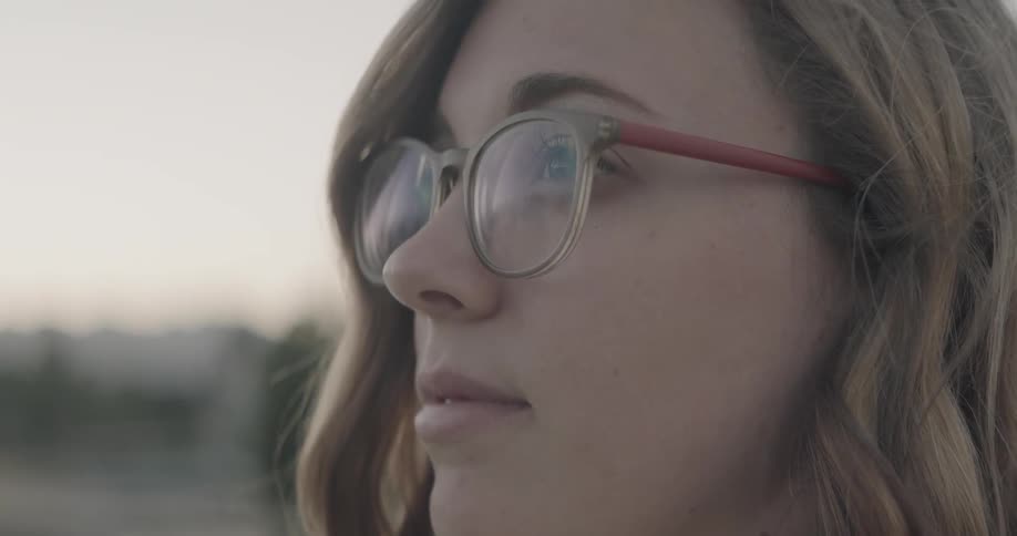 Woman wearing glasses standing outside looking out