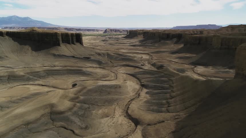 Dry streams and tracks are covering an eroding desert valley in daylight