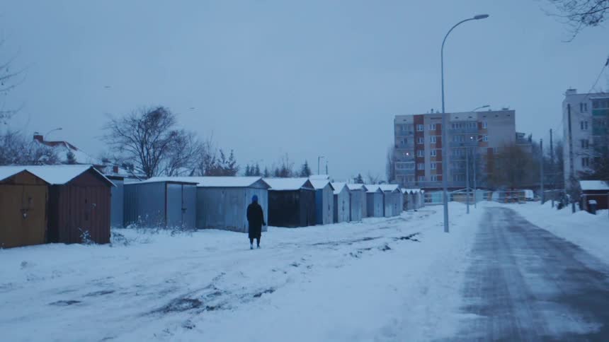 Person walks on a snowy sidewalk in a city