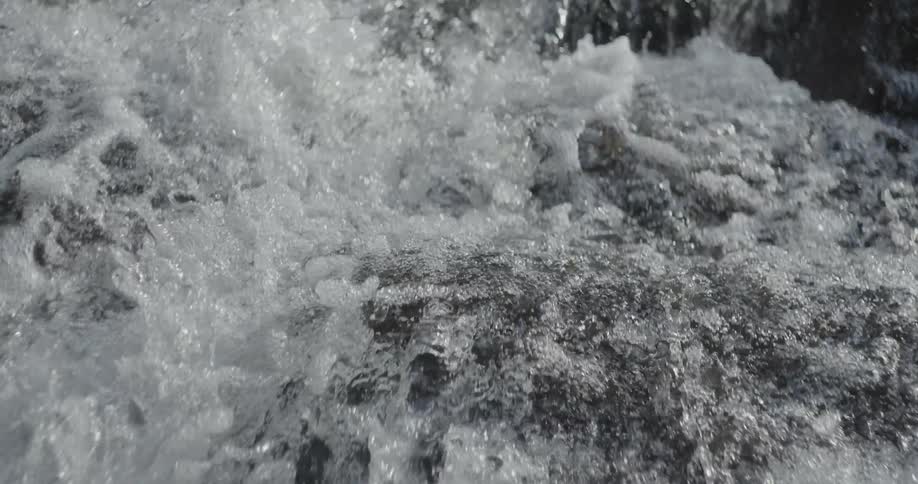 Water is gushing down onto rocks and splashing around