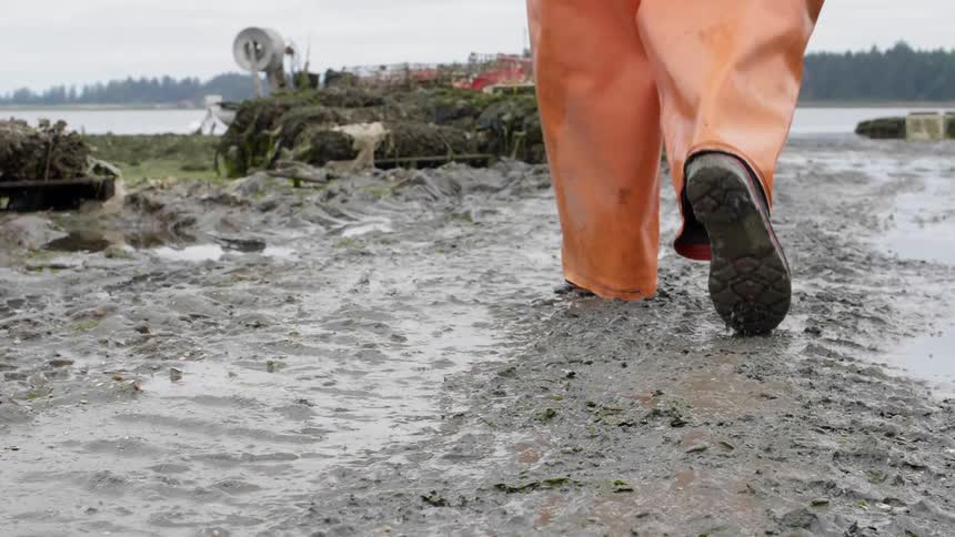 Man in an orange jumpsuit walks through the mud