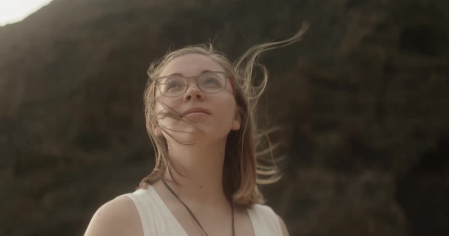 Woman wearing glasses turns around as she stands under the bright sun