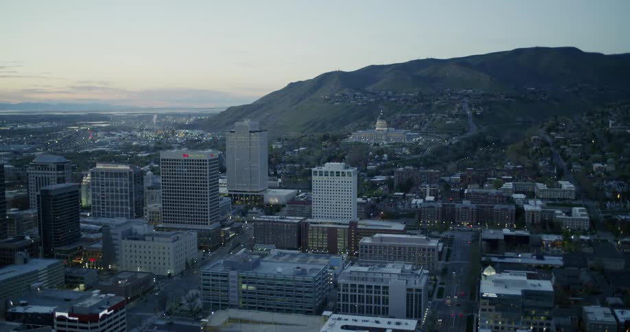 Dusk is falling on a city at the base of foothills