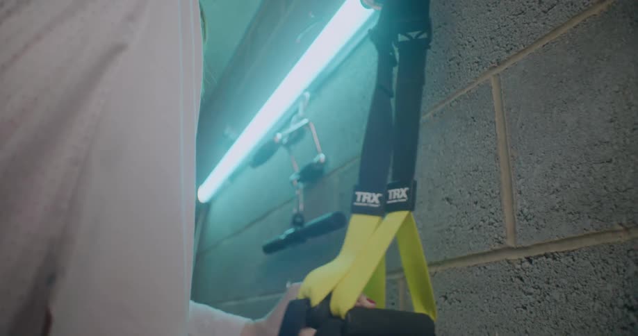 Woman hangs up straps on a gym wall