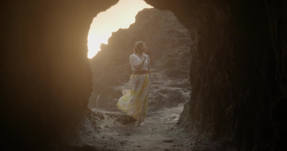 Woman stands on a windy beach at sunset