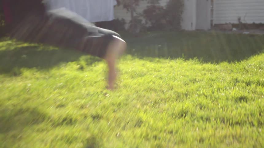 A barefoot man running and pulling on a pair of jeans outside