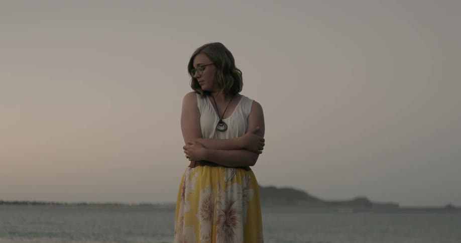 Woman stands with her arms crossed while her head is turned