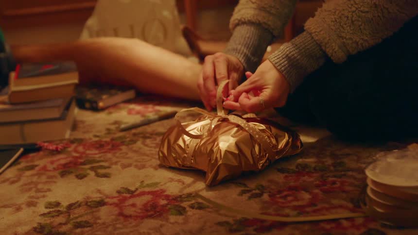 Woman ties a ribbon on a present