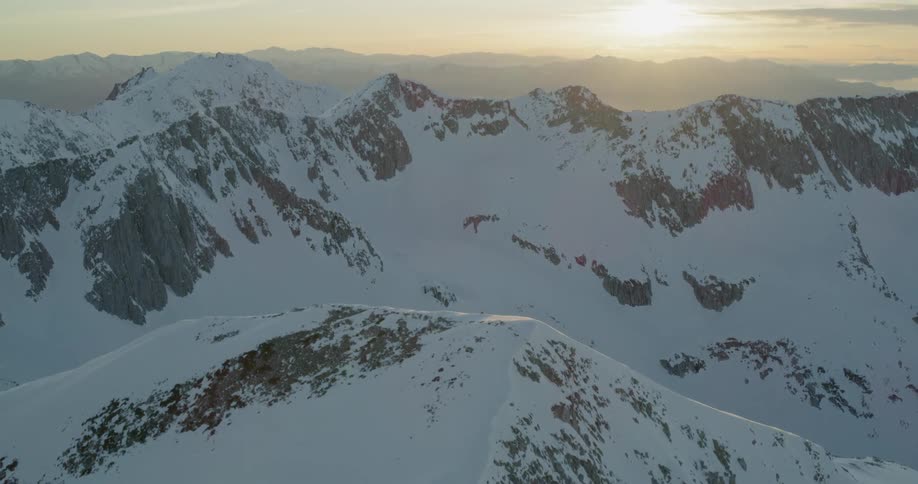 The sun sets over snowy mountains